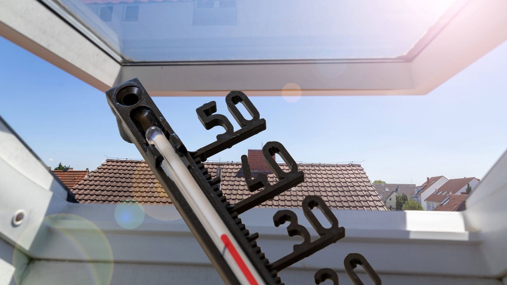 Ein Thermometer vor einem Dachfenster zeigt heiße Raumtemperatur an