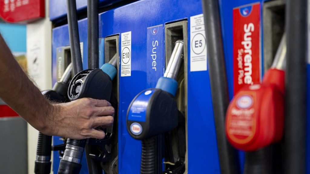Ein Autofahrer hängt an einer Tankstelle eine Zapfpistole in die Zapfsäule. 