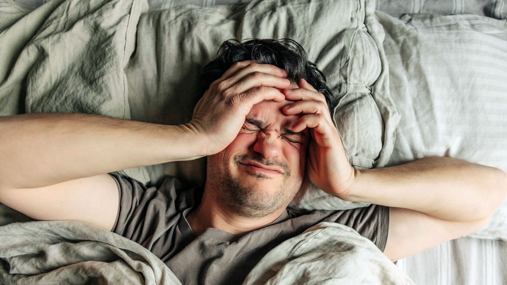 Foto: Symbolbild: ein Mann liegt im Bett und greift sich an den Kopf