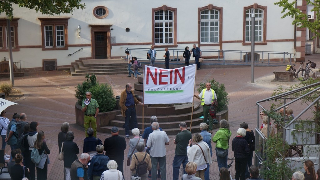 Foto: Menschen versammeln sich mit einem großen Schild auf einem Platz
