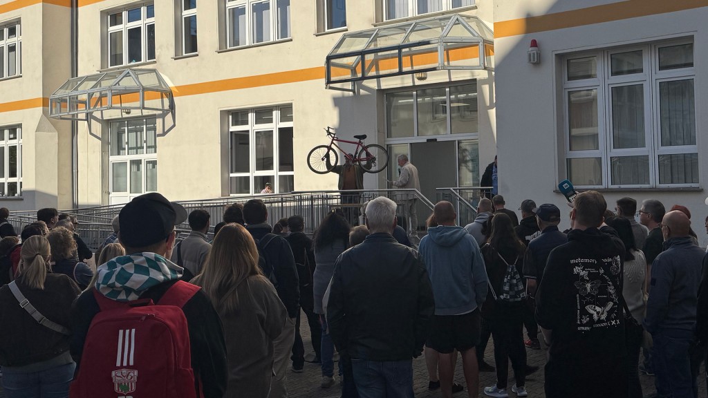 Ein Mann hält ein Fahrrad hoch, welches gerade versteigert werden soll