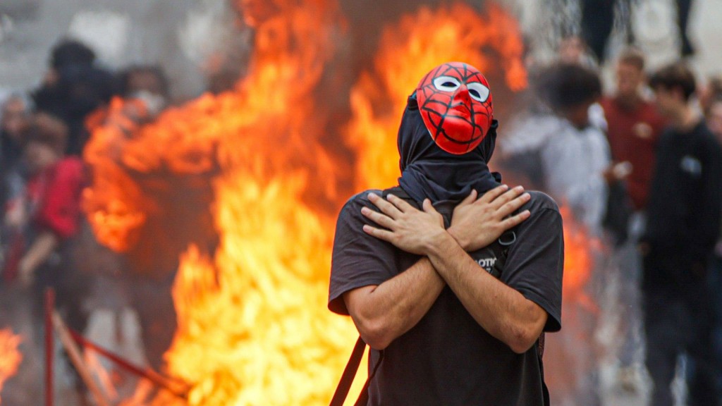 Mann mit roter Maske vor brennendem Feuer (Bild aus der Stadt Pau im Südwesten Frankreichs)