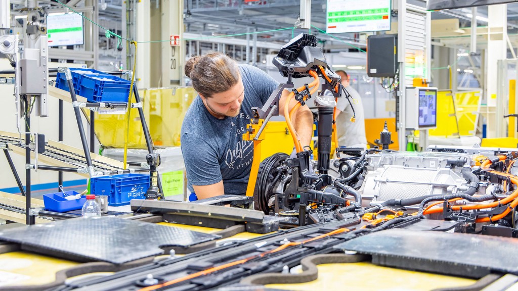 Foto: Eine Person steht an einem Produktionsfließband in der Autoindustrie