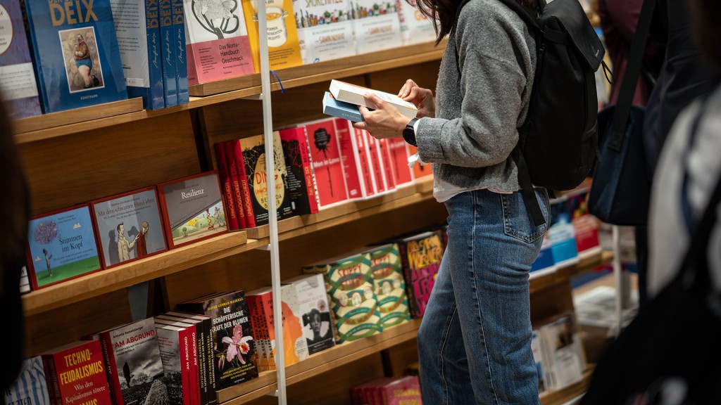 Eine Frau mit zwei Büchern vor einem großen Bücherregal